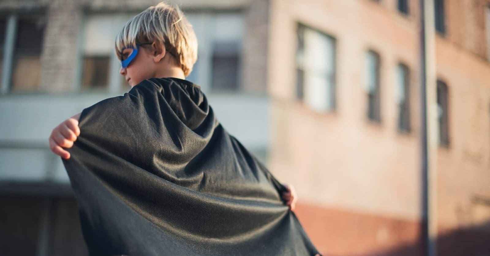 selective focus photography of boy wearing black Batman (a super hero) cape