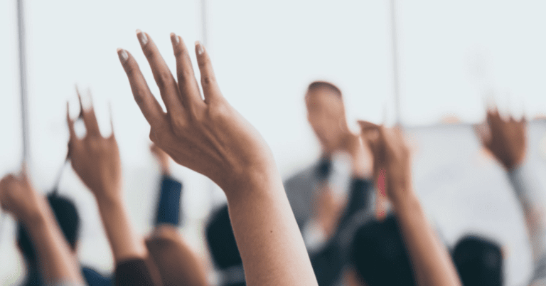 people raising their hands to actively engage with the speaker