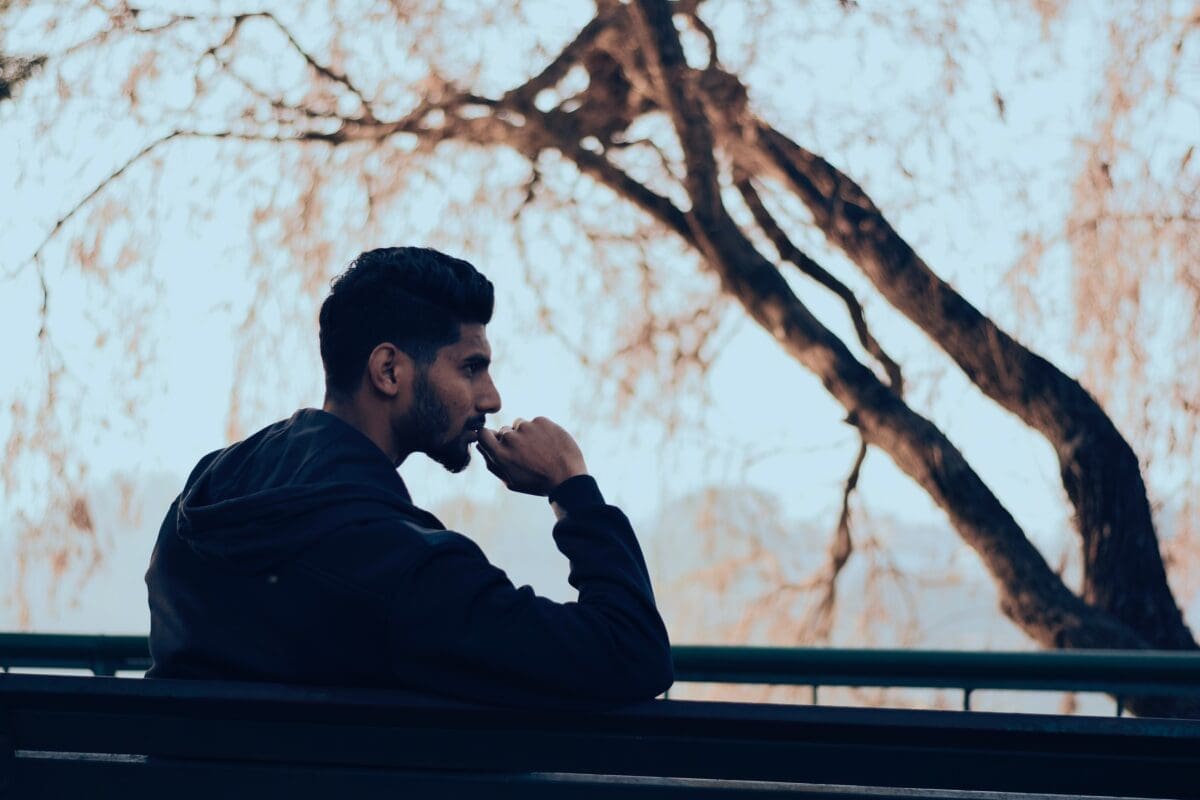 A person deep in thought with a leafless tree in the background