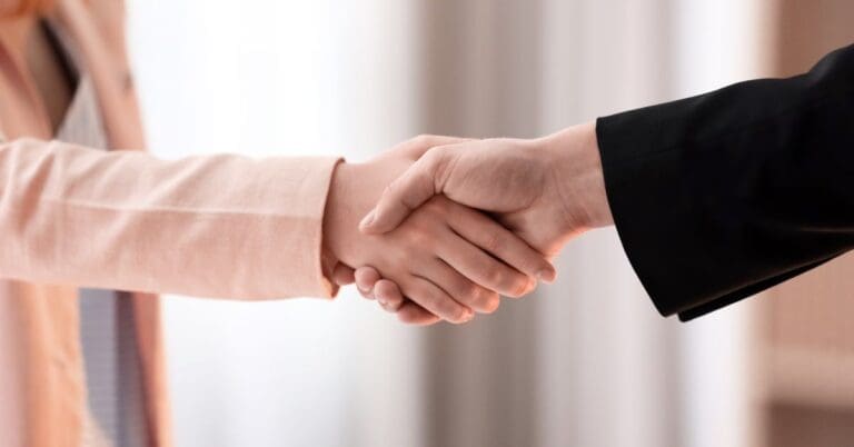 a woman and a man shaking hands to signify an agreement. focus on the hands only, faces are not visible.