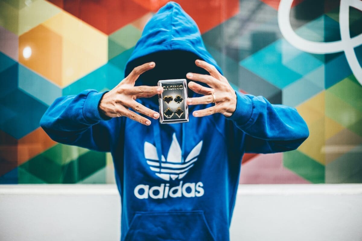 person with face not visible in an adidas sweatshirt, doing a magician like card trick
