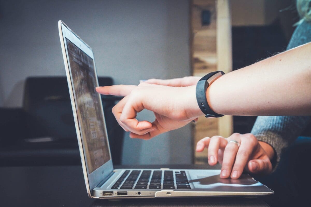 Hands pointing towards a laptop screen
